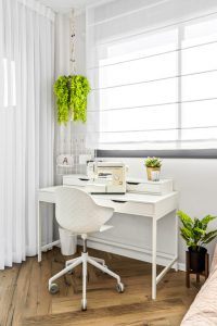 שולחן כתיבה לבן עם מכונת תפירה וצמח בחדר