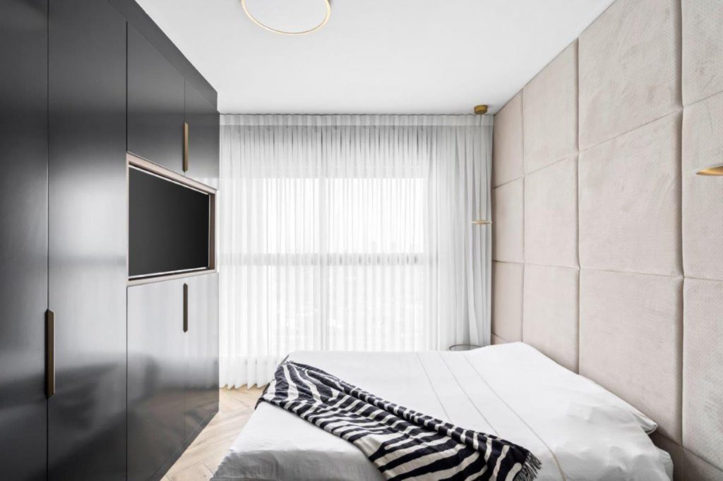 מיטה עם שמיכה בשחור לבן בחדר עם טלוויזיה